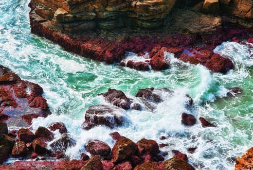 ocean waves crash on to rocks at the coast