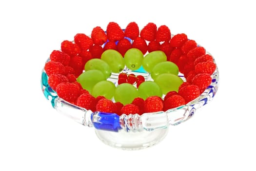 Grape, raspberry and red currant on a glass plate, isolated on white