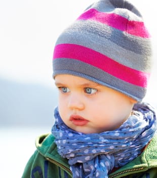 Portrait of sad and serious little baby boy in springtime.