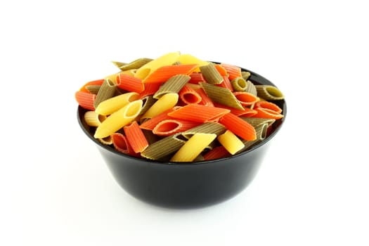 Raw colored pasta in black bowl isolated on white background