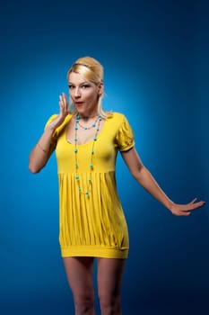 Amazing woman in yellow dress surpized on blue background