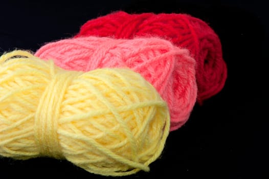4 balls of wool of different colors on a black background
