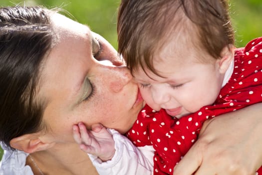 mother kissing baby in the park