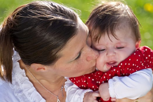 mother kissing baby in the park