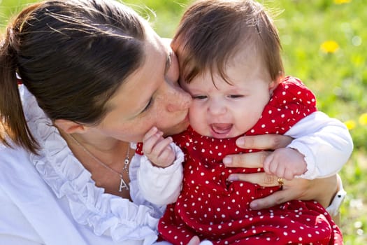 mother kissing baby in the park
