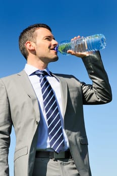 businessman in suit is drinking fresh water in a bottle