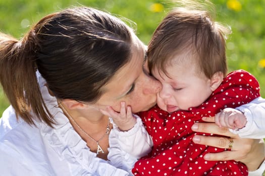 mother kissing baby in the park