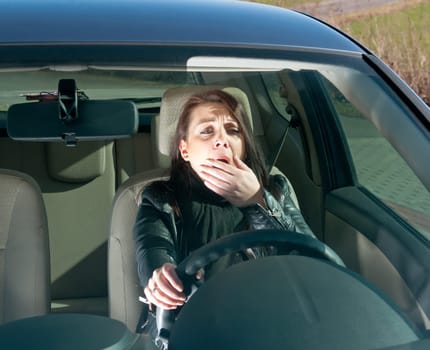 Young woman yawning in the car