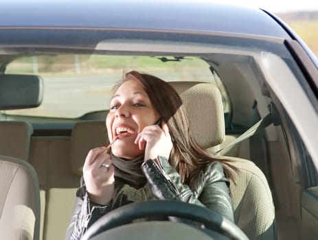 Young woman with lipstick and mobile phone in car