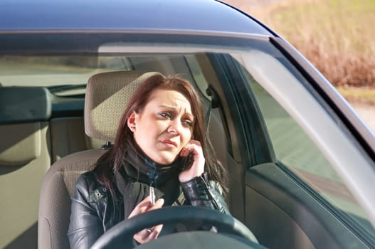 Young woman with cigarette and mobile phone in the car