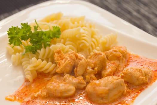 Chicken pieces with Pasta in Paprika Cream Sauce. Decorated with parsley. The dark setting.
