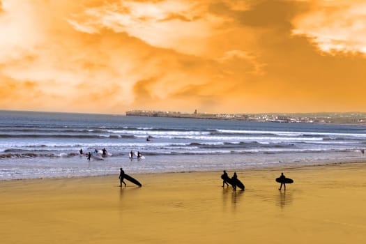 surfers walking on the beach in lahinch county clare ireland as the sun goes down