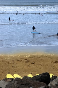 surfers wading out on the beach in lahinch county clare ireland on a beautiful day
