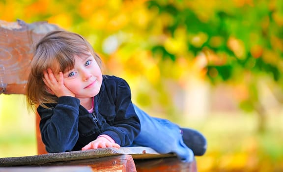 little girl sitting on the bench in park