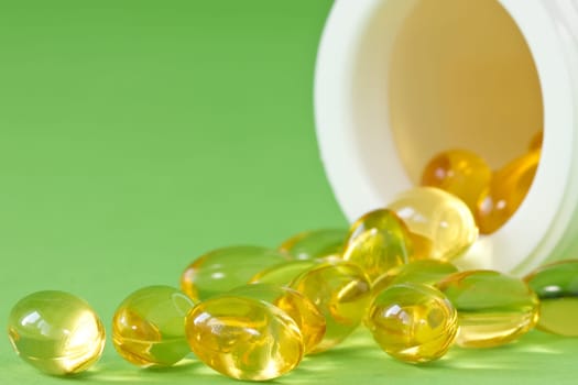 pill bottle with yellow pills on green background