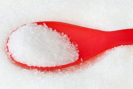 red plastic spoon with a white sugar