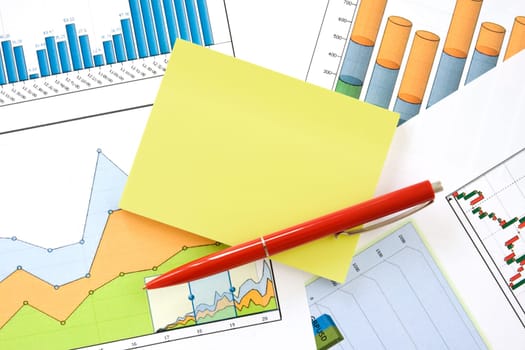 red pen and yellow memo over financial charts