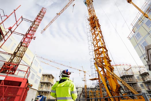 geodetist with geodesy measuring instrument, giant building site, wide angle view