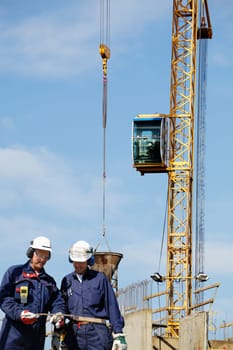 building-workers with large crane in background, general scenery inside construction site