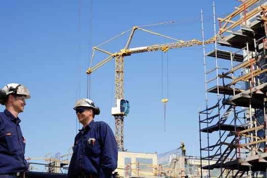 two building-workers, engineers, inside large construction-site
