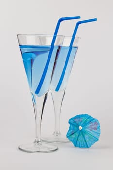Two Blue Cocktails with blue straws and a blue umbrella