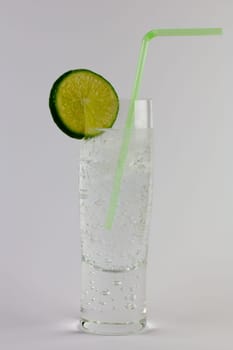 A glass of gin and tonic with ice and lime