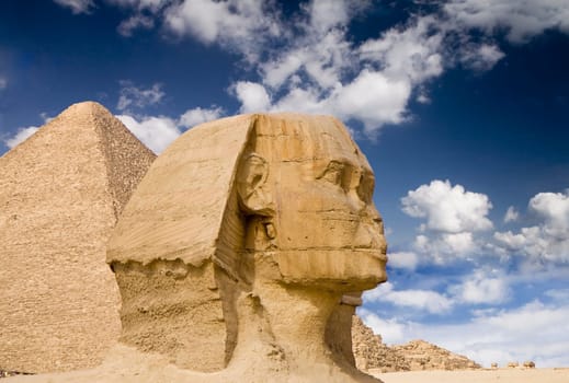 Ancient Egyptian Sphinx with old historic pyramid behind