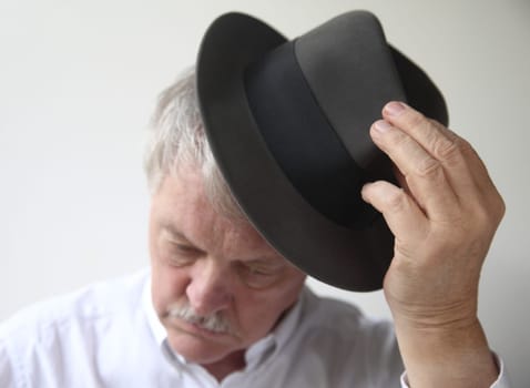 an older man puts on a fedora