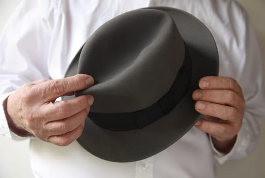 man holds a gray fedora