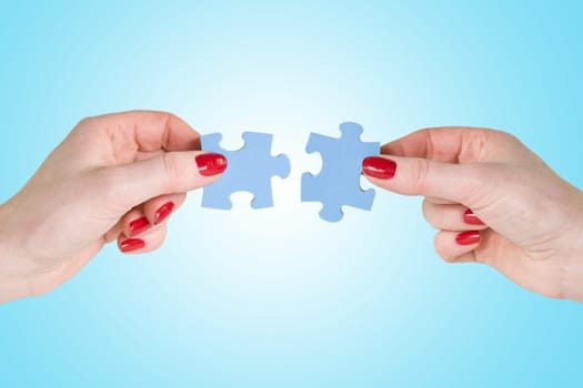 hands  connecting different pieces of blue puzzle
