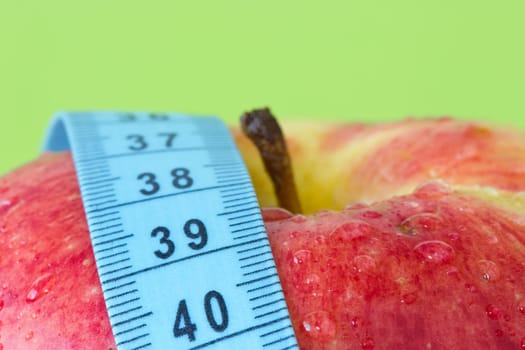 healthy food concept. red apple with blue measure tape.