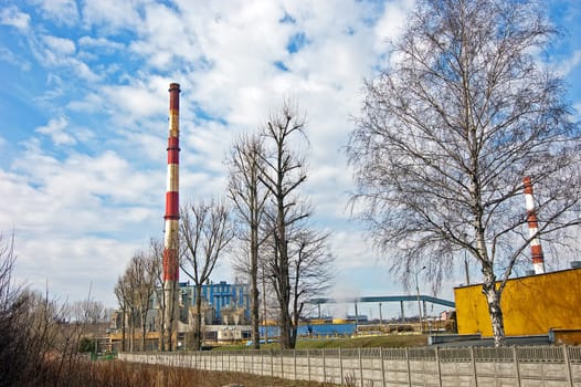 With a smoking chimney power plant on a sunny day