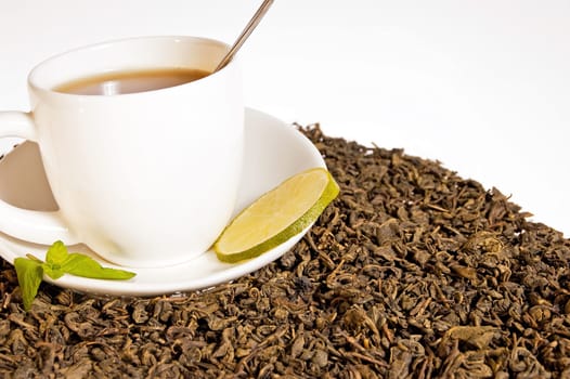 Green tea leaves and a cup of brewed tea with mint leaves