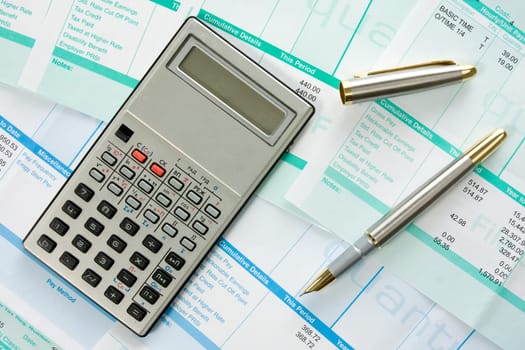 calculator,pen  and payroll summary details