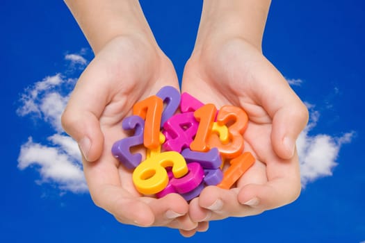 child hands with color numbers on sky background