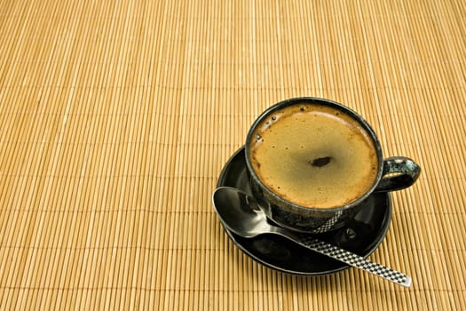 black coffee cup on striped bamboo tablecloth