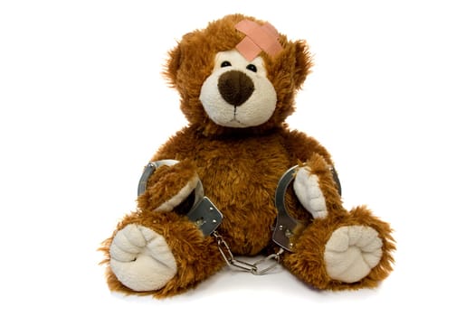injured and handcuffed Teddy bear on white background