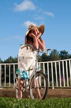 Beautiful young girl with big hat and bicycle