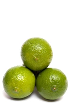 Three green limes against white background
