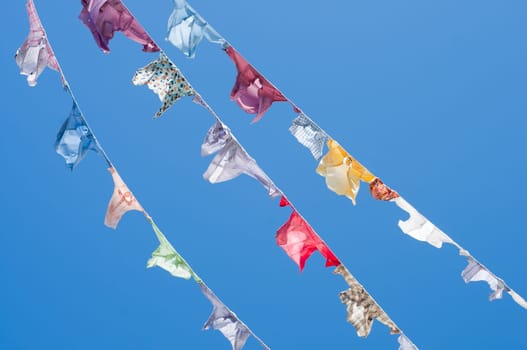 A group of colored shirts on clothesline in front of blue sky