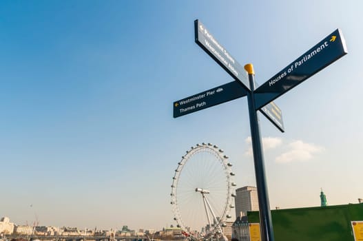 LONDON, UK - APRIL 02: Sign post directing to famous tourist attractions, with London Eye in the background . April 02, 2012 in London.