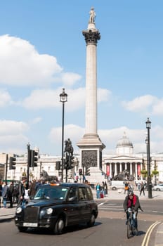 LONDON, UK - APRIL 02: Famous black cab driving by Trafalgar Square, with Nelsons Column in the background. April 02, 2012 in London.