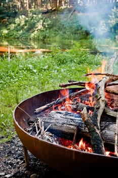 Campfire in the wilderness with small pond