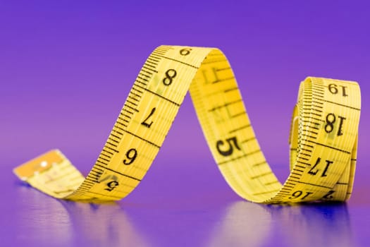 yellow measure tape on purple background