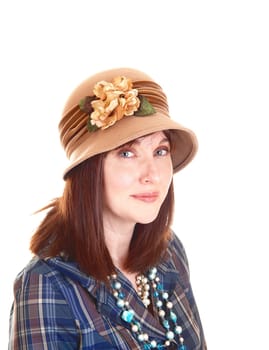 A portrait of a beautiful middle aged woman in a blue shirt and necklace with a beige hat with flowers on, and red hair for white background.