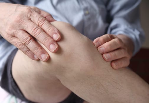 a man with his hands on a painful knee joint