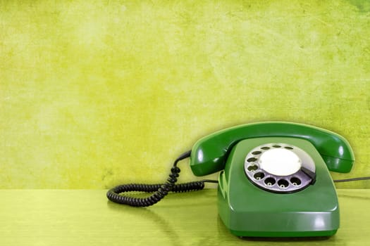 old scratched phone against green wall background