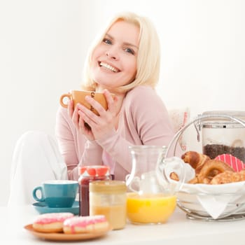 Young and blonde woman sitting at a breakfast table