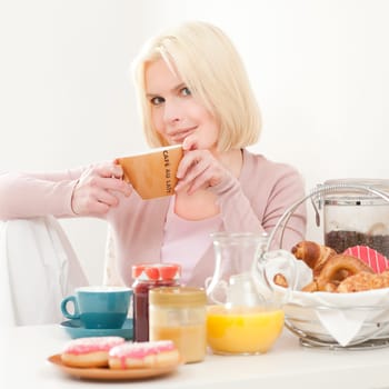 Young and blonde woman sitting at a breakfast table