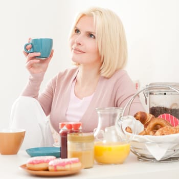 Young and blonde woman sitting at a breakfast table
